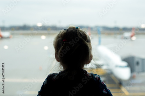 child at the airport looks at the plane outside the window. Airline travel concept.