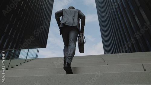Back view of businessman walking on stairs in hurry