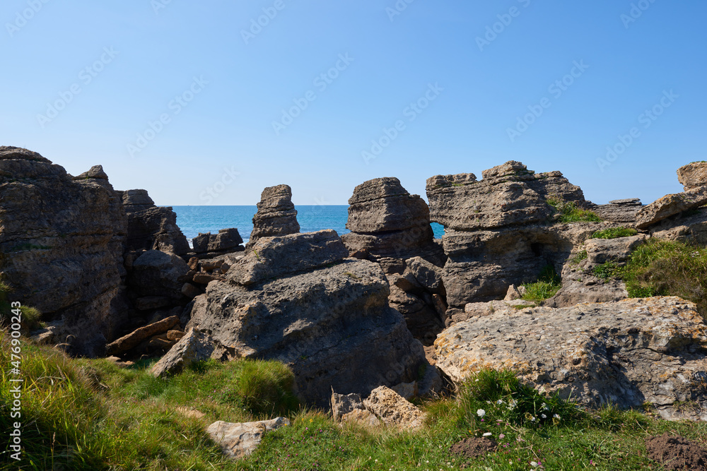 Cliffs surrounded by green vegetation under a blue sky.