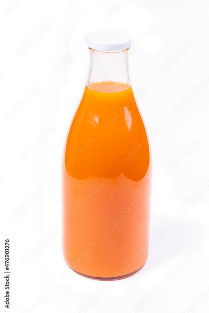 white background. a glass bottle with an orange liquid in it. juice of tangerine, and carrots, as well as pumpkins white background. a glass bottle with an orange liquid in it. juice of tangerine, and carrots, as well as pumpkins