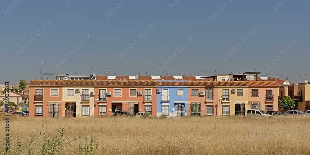 Colourful row of houses with grass field and cars in front in the Spanish countryside in the village of Santiponce Colourful row of houses with grass field and cars in front in the Spanish countryside in the village of Santiponce