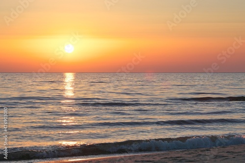 Calm seashore in the evening. Hazy sun at sunset.