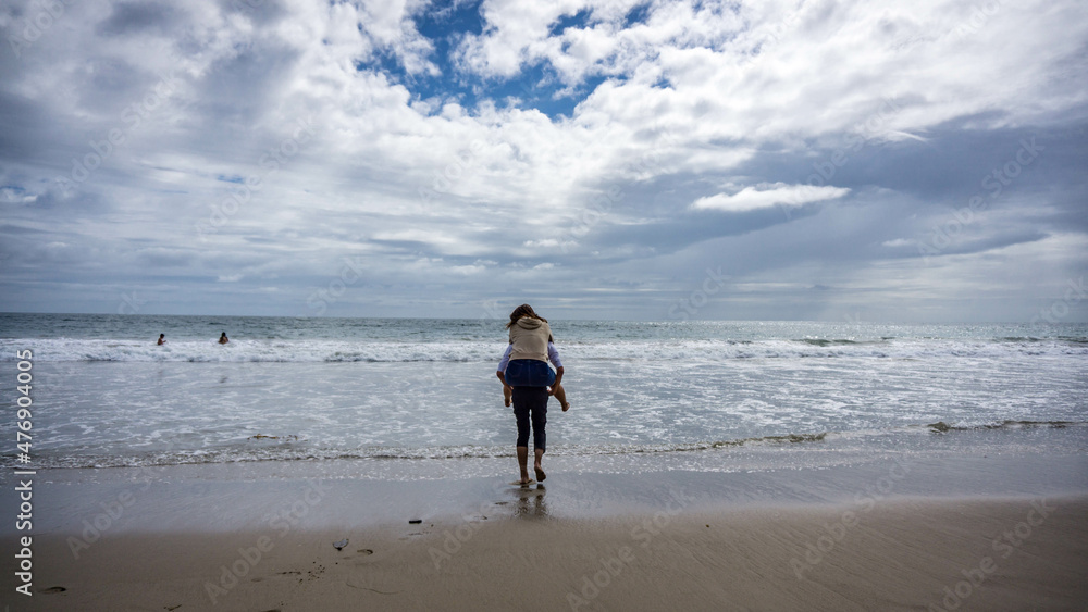 Asian girl riding piggyback on a asian guy at Malibu Beach, California, USA