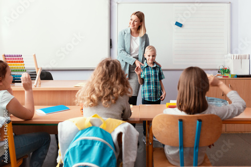 Young happy teacher introduces the new student to the class photo