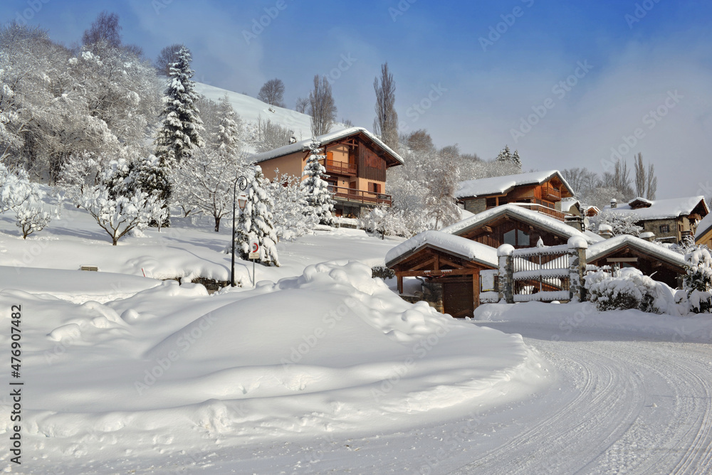  chalets  in alpine village covered with snow at the end of a white rural road