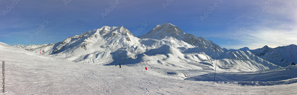 panoramic view on peak mountain covered with snow and ski tracts on the slopes