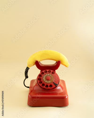 retro red telephone with yellow fresh banana imitating phone handset.aesthetic still design.communication or invitation concept idea
