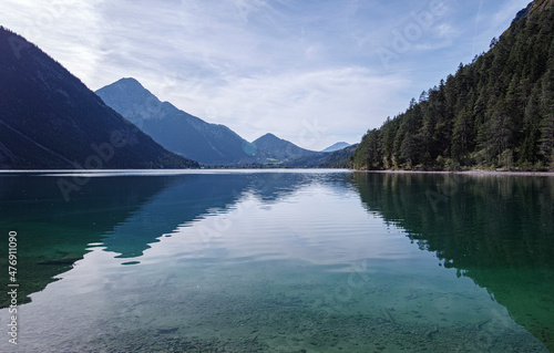 Alpiner Bergsee Heiterwanger See im morgendlichen Licht an einem kalten Tag im Herbst mit leicht bewölktem Himmel in Tirol, Österreich