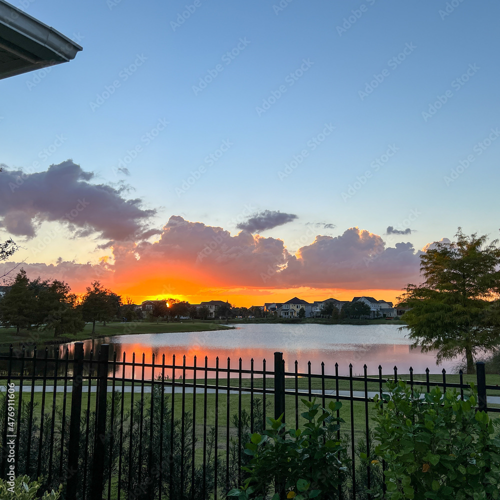 beautiful pink, orange and blue sunset reflecting on a lake in a suburban neighborhood.