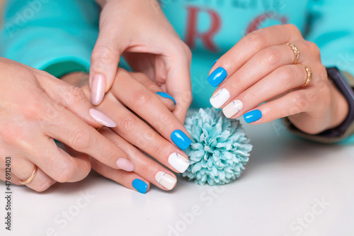 Manicurist holding female hands with romantic manicure nails, white and blue gel polish