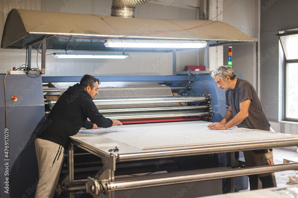 Technician works on large industrial textile sublimation heat printing machine Technician works on large industrial textile sublimation heat printing machine