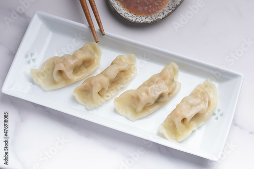Pork gyoza in a white plate with soy sauce