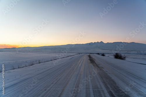 Winter sunset in the mountains. Frozen road.