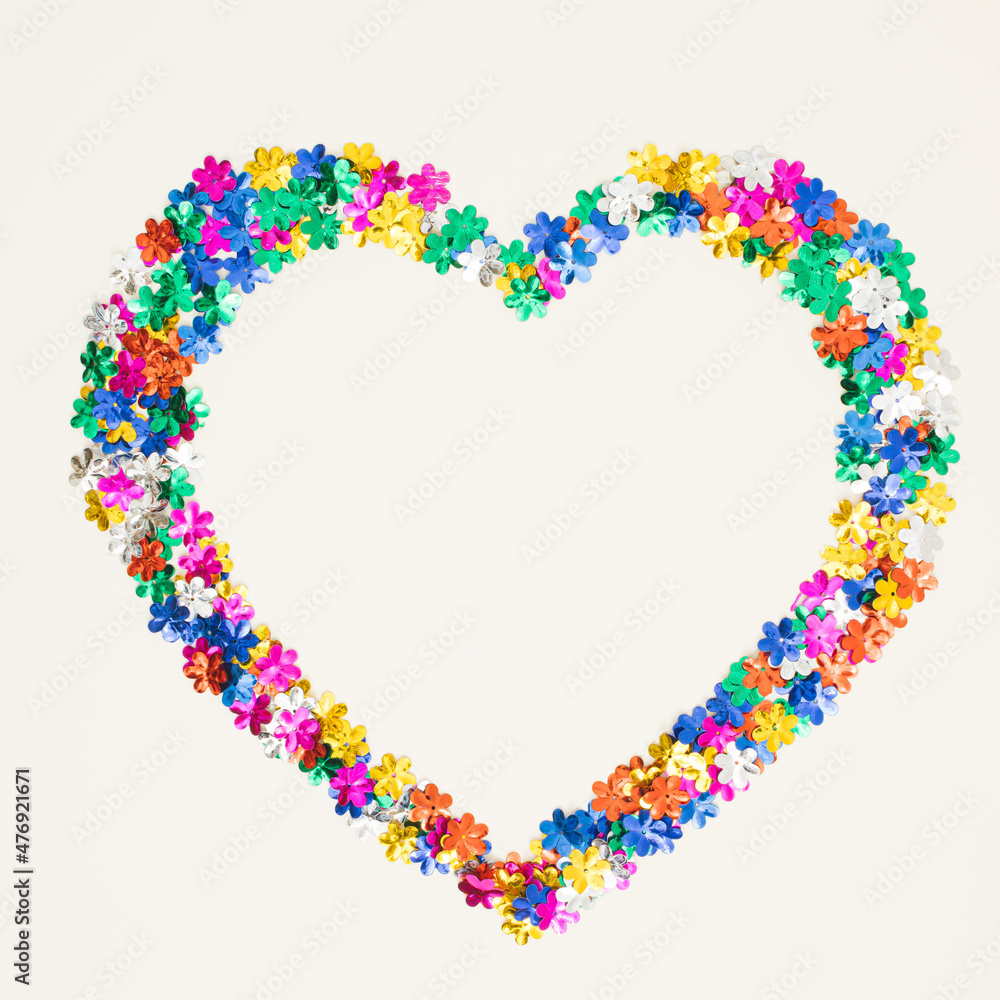 Heart symbol made of flower shaped glitter on white background. Love valentines or woman's day concept. Minimal flat lay.