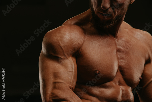 A close-up shot of a part of a torso of a bodybuilder during a workout.