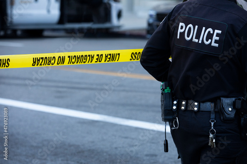 Detailed view of police uniform and cordon tape sealing off an active crime scene.