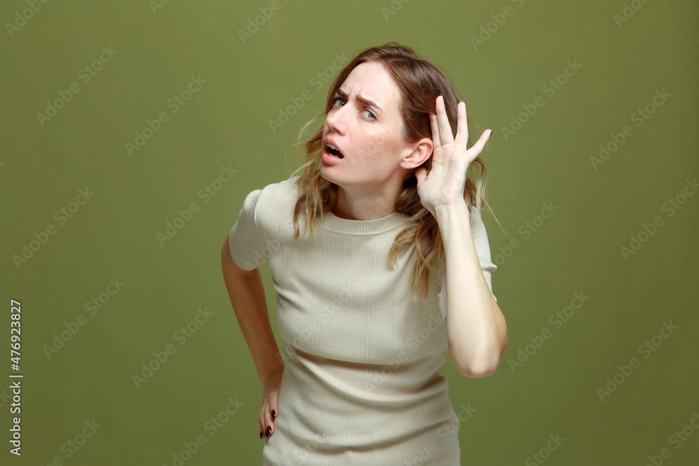 Hearing gesture. Young woman hold hand near ear, try to listen information. Misunderstanding, communication problems