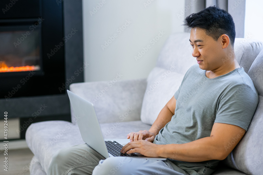 Handsome young man using his laptop while relaxing on the couch at home. Handsome young man using his laptop while relaxing on the couch at home.