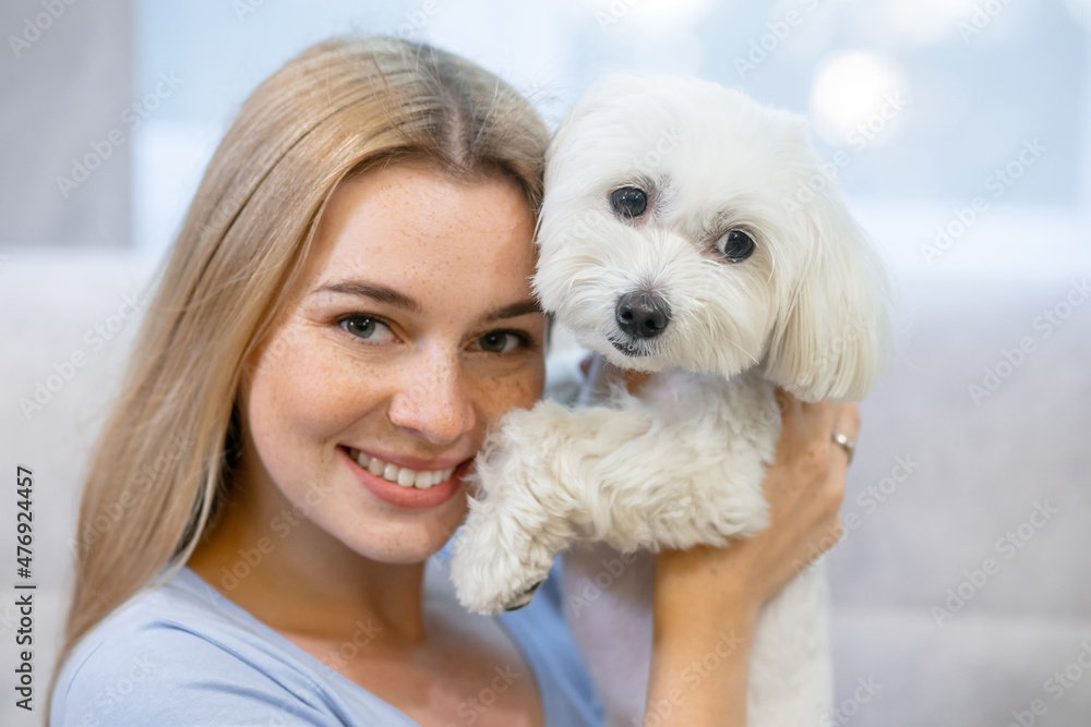 close-up of a young girl. she smiles and keeps her beloved pet a white lapdog. close-up of a young girl. she smiles and keeps her beloved pet a white lapdog.