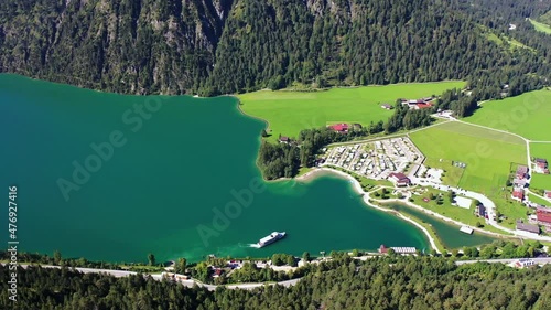 aerial panoramic video of north part of Achen lake near Achenkirch in Tirol during sunny summer day with a ferry boat leaving the boat stop Scholastika - the camp ground is located close to the lake  photo