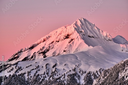 Sunrise in the mountains in winter. Pink glowing sky over snow covered peak. Whistler. British Columbia. Canada photo