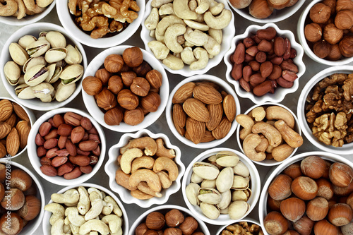 Colorful mix of various nuts: peanut and cashew, hazelnut and almond, pine nuts and walnut; healthy diet snack; vegan food background