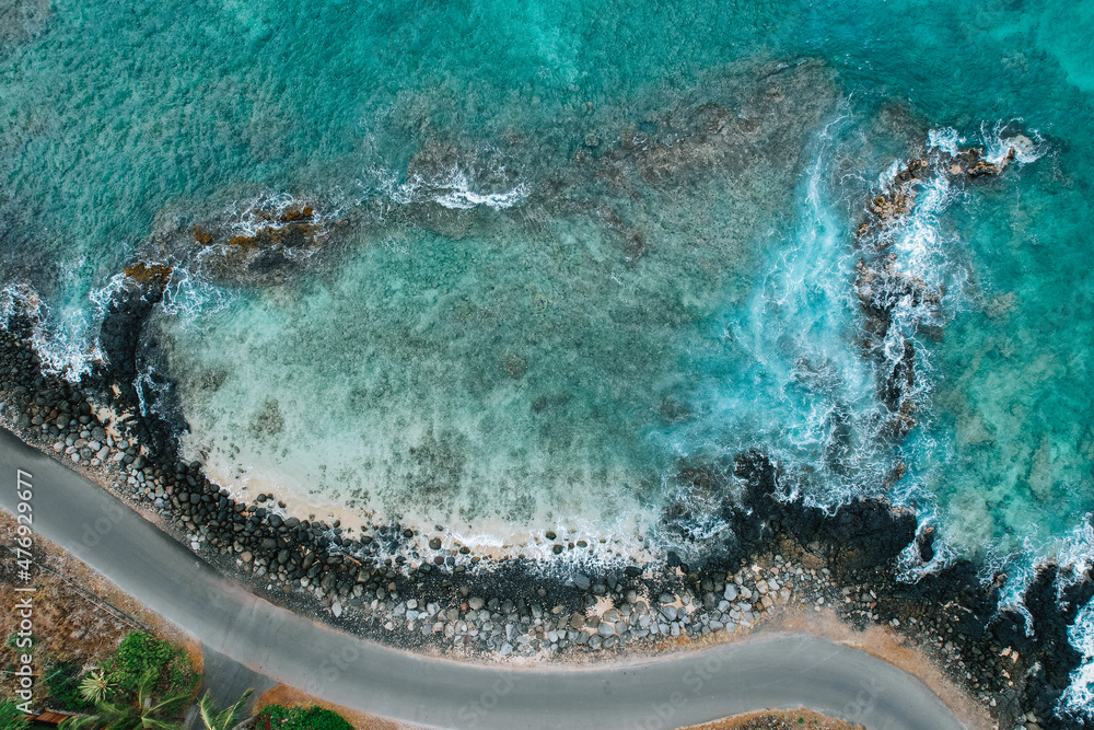 Drone view of a turquoise blue water in Maui, Hawaii bay next to a road