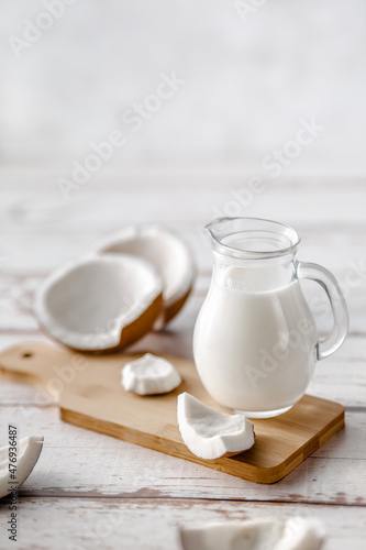 A jug of milk next to fresh coconuts
