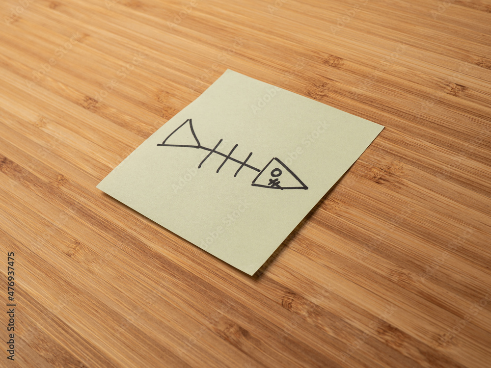 A paper sticker pasted on a wooden surface with the image of the fish skeleton symbol A paper sticker pasted on a wooden surface with the image of the fish skeleton symbol