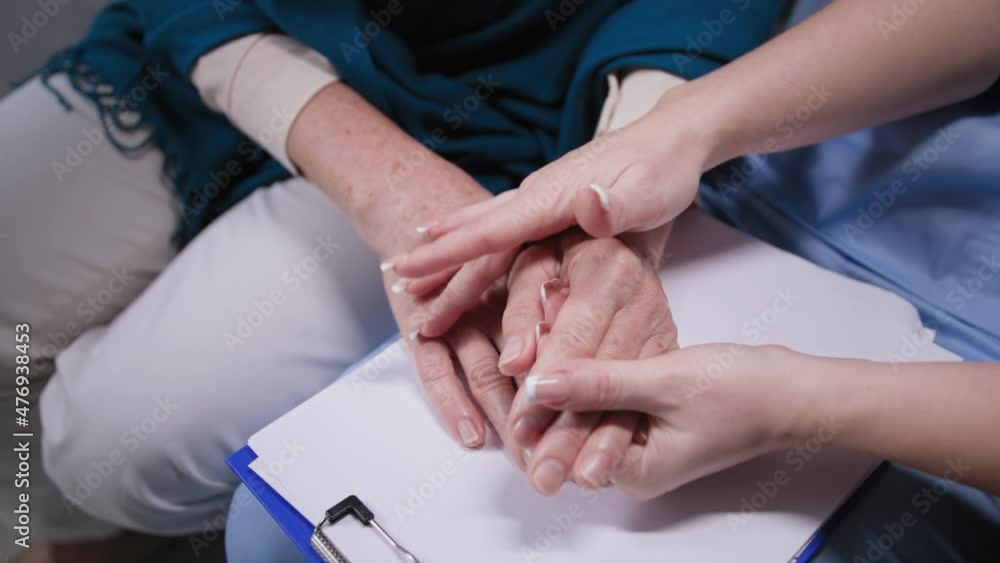 care to senior people, young woman doctor holds elderly female hands during medical visit at home