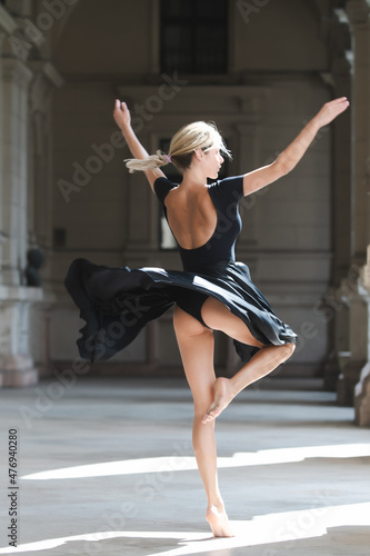 Street style photo of elegant fashionable woman movement in skirt. Sexy black dress. Sensual woman dancing outside, ballerina dance in black dress.