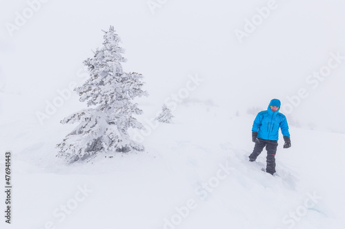 Hiker snowshoeing through high contrast trees in a snow storm fog