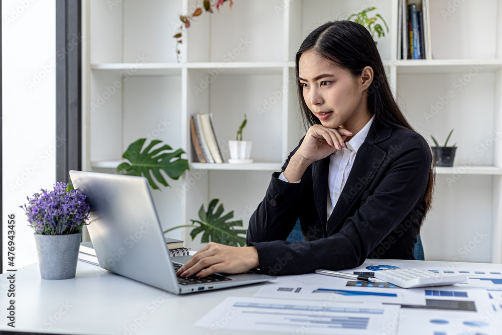 Beautiful Asian young woman looking at information on a laptop, concept image of Asian business woman working smart, modern female executive, startup business woman, business leader woman. Beautiful Asian young woman looking at information on a laptop, concept image of Asian business woman working smart, modern female executive, startup business woman, business leader woman.