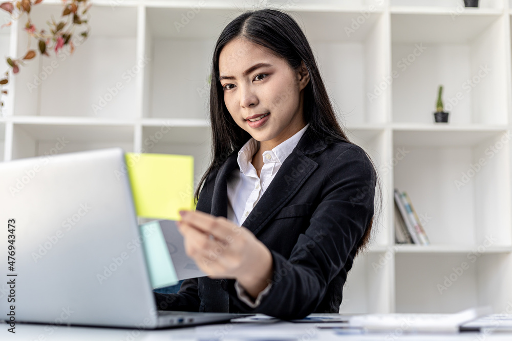 Woman working in a private office, a business woman owner of a company holding a notepad with notes on her laptop, she is checking company financial documents. Concept of company financial management. Woman working in a private office, a business woman owner of a company holding a notepad with notes on her laptop, she is checking company financial documents. Concept of company financial management.