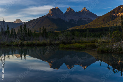 A beautiful reflection of the Three sisters in Policeman Creek, Hope, Faith and Charity in Canmore, Canadian Rockies.