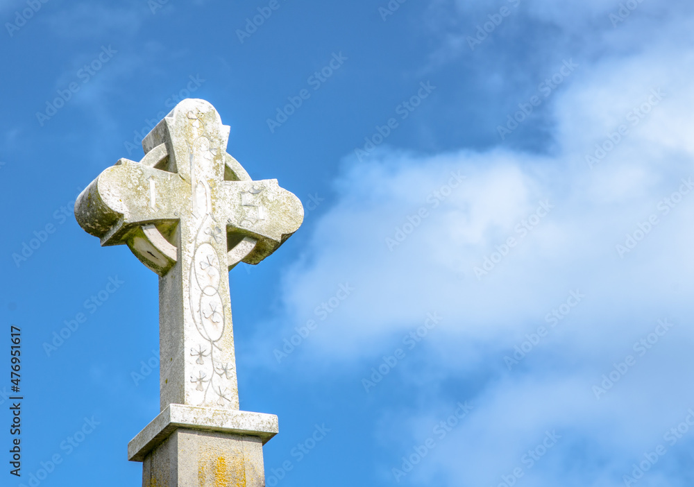 Antique stone cross standing against cloudy sky day.