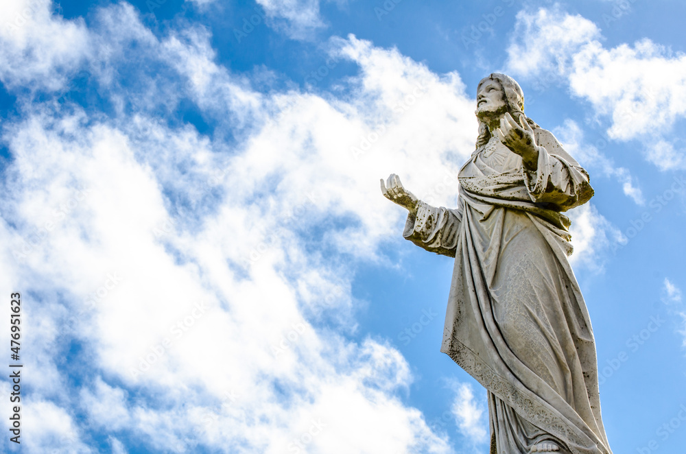 Fototapeta premium Jesus Christ statue standing against the cloudy sky day.