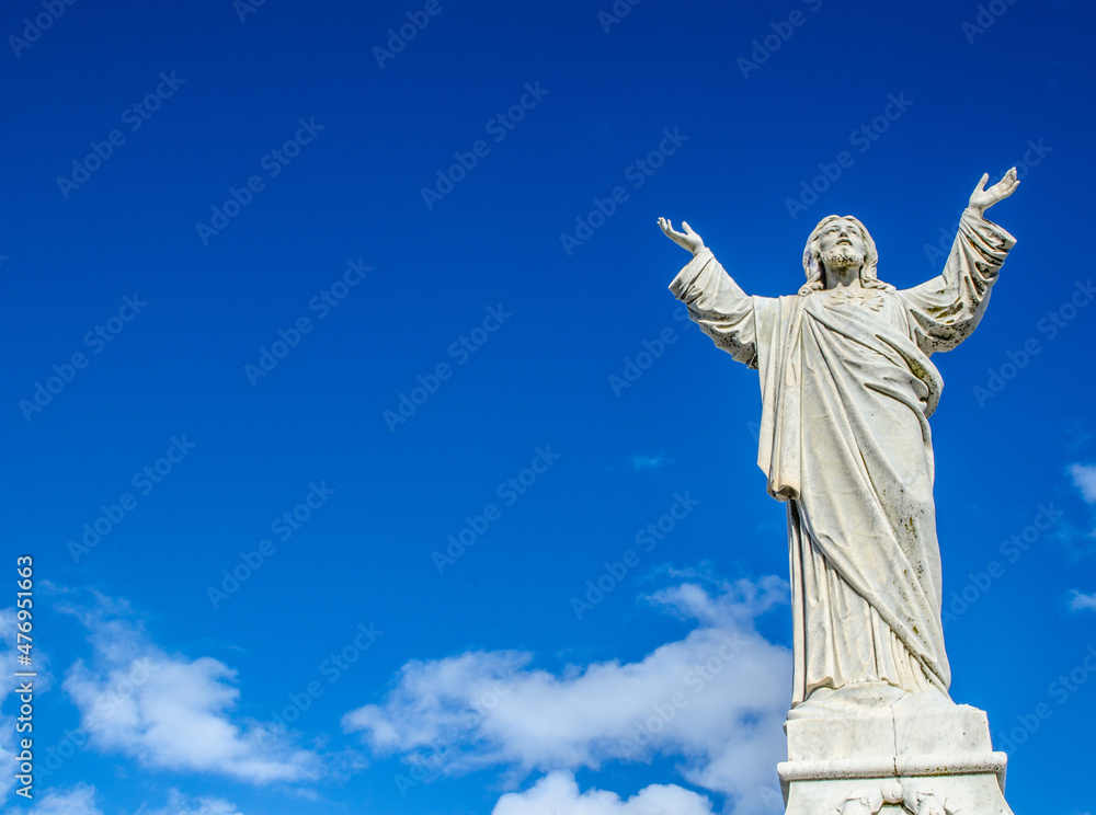 Jesus Christ statue standing against the blue sky.