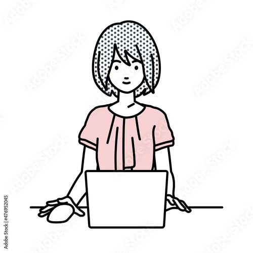 デスクで座ってPCを使っているオフィスカジュアルの女性