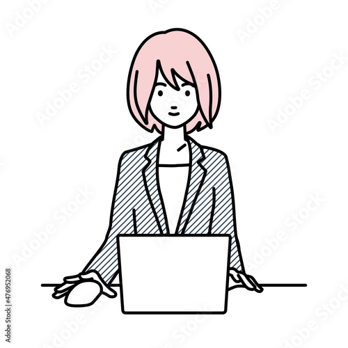 デスクで座ってPCを使っているスーツの女性