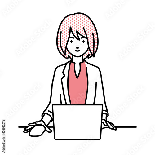 デスクで座ってPCを使っているジャケットの女性