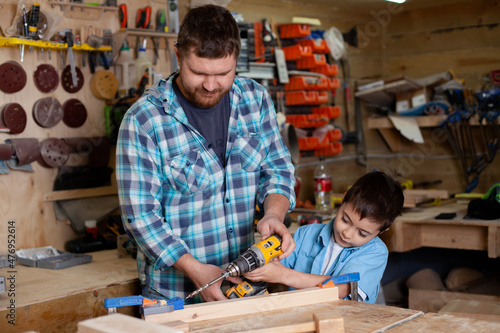 Father carpenter and son boy work in the workshop. Master dad teaches his son carpentry. Continuity of generations. Small business.