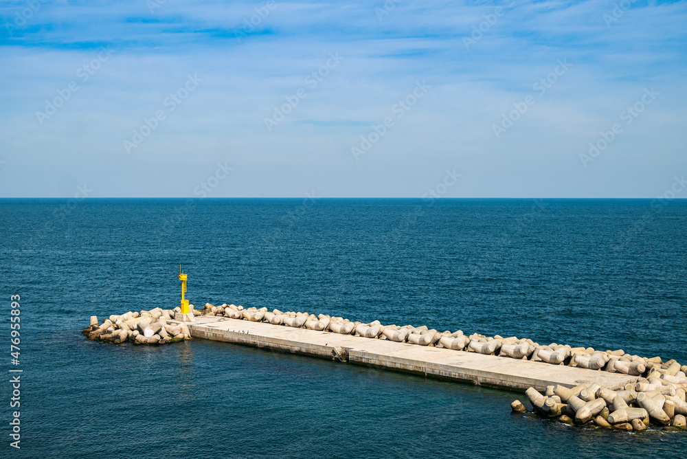 Coast breakwaters protecting from large waves with sea water background.