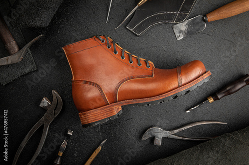Handcrafted brown leather shoe with cobbler tools on the backgound