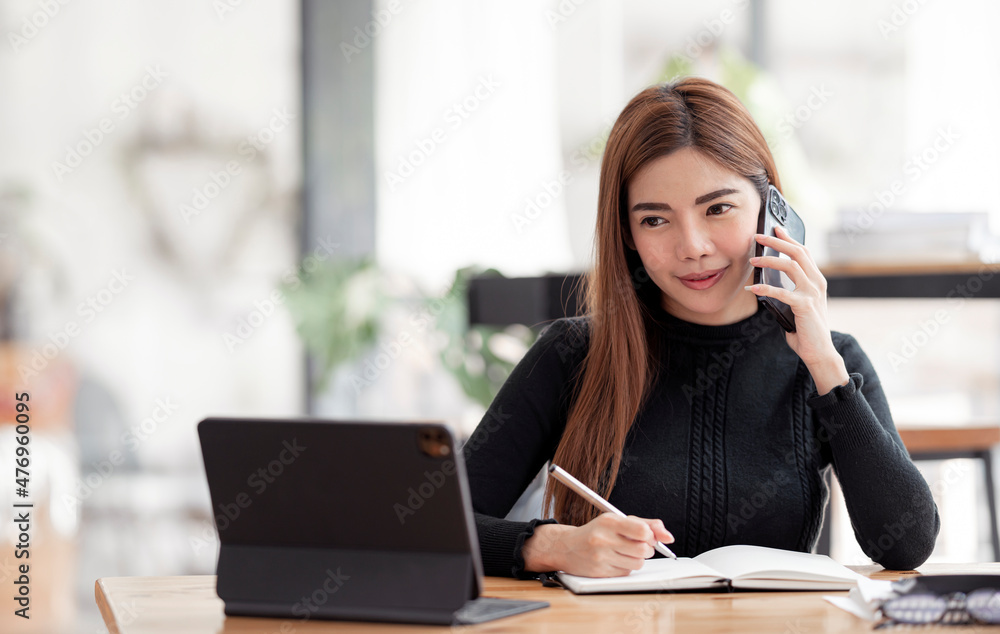 Portrait of beautiful smiling young entrepreneur businesswoman using mobile phone and working in modern work station.