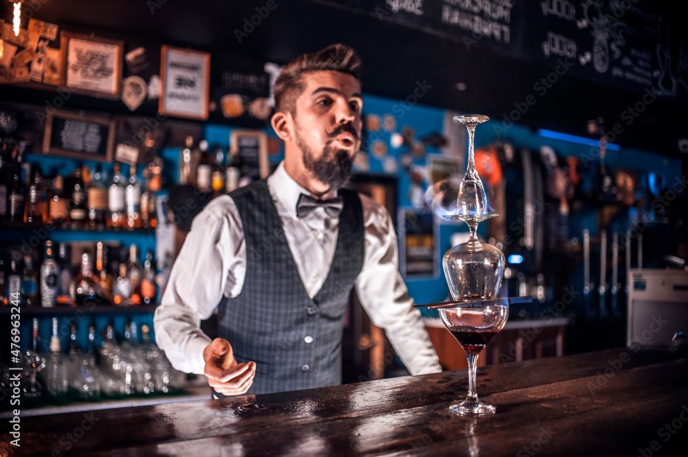 Charismatic barman formulates a cocktail at the bar counter