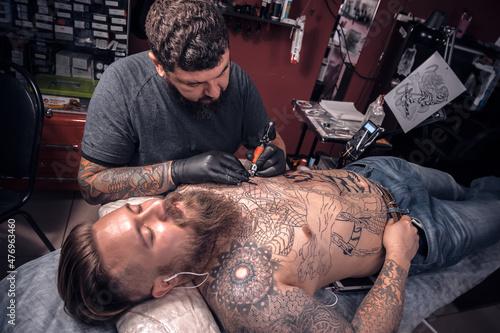 Professional tattooer demonstrates the process of getting tattoo in tattoo studio photo