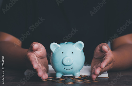 Woman hand holding piggy bank on wood table, saving money wealth and financial concept, Business, finance, investment, Financial planning,vintage picture style concept.