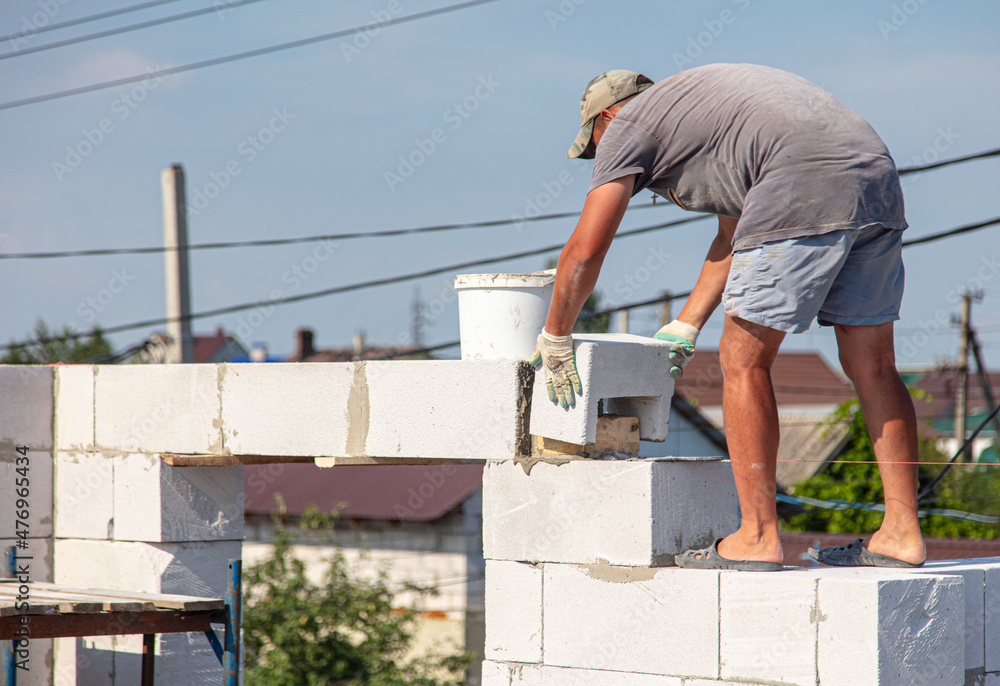 A worker builds the walls of a house from aerated concrete bricks. A worker builds the walls of a house from aerated concrete bricks.