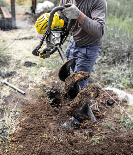 A worker is drilling soil for a gate